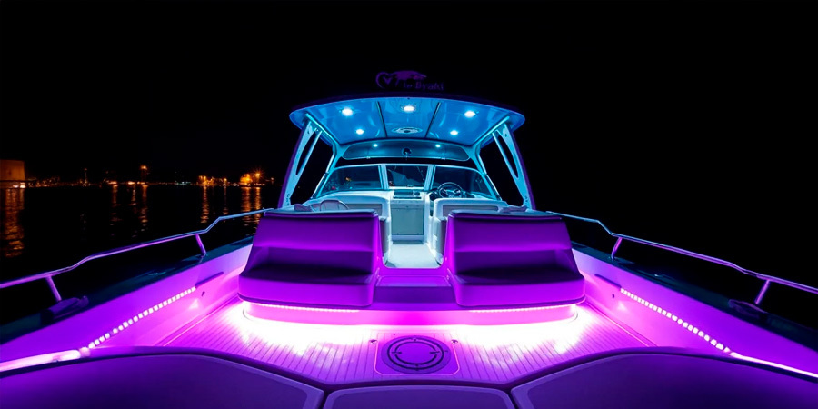  A luxury boat illuminated with purple and blue LED strip lights, highlighting the seating area and interior at night on the water.