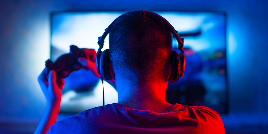 Boy playing videogames, the images sync with the back lights of the TV