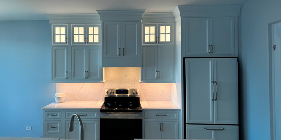 A contemporary kitchen with white cabinets, a stainless steel stove, and under-cabinet lighting that provides functional task lighting and adds a stylish touch.