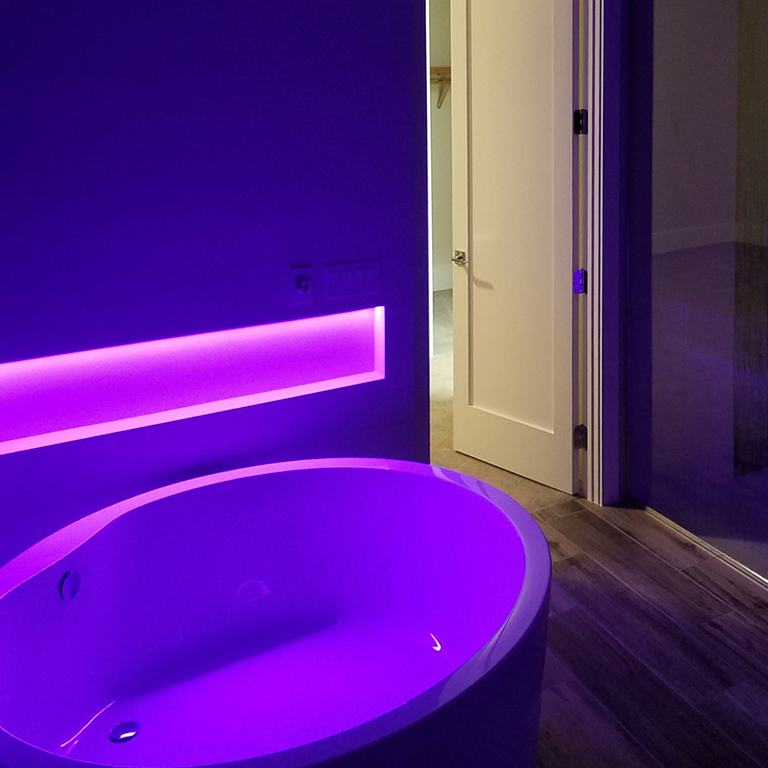 Bathroom niche and bathtub illuminated by purple RGB light