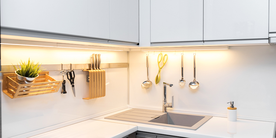 detail of aluminum channels and led lights under de cabinets of a modern white-kitchen