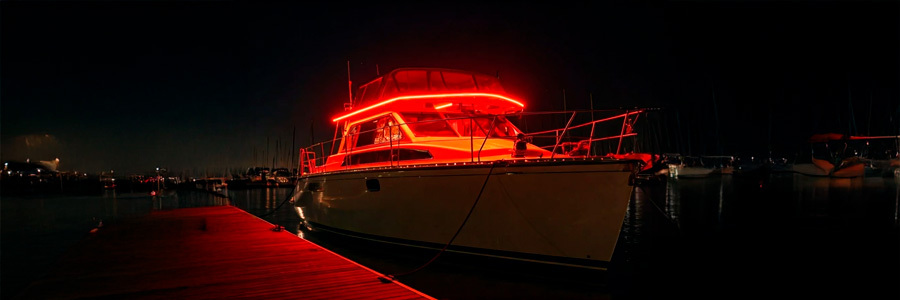 A boat illuminated with vibrant red LED strip lights, creating a striking and stylish look while docked at night.