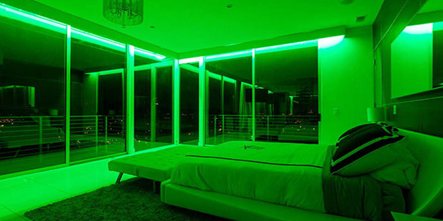 Modern bedroom with RGB green LED strip lighting along ceiling and large floor-to-ceiling windows.