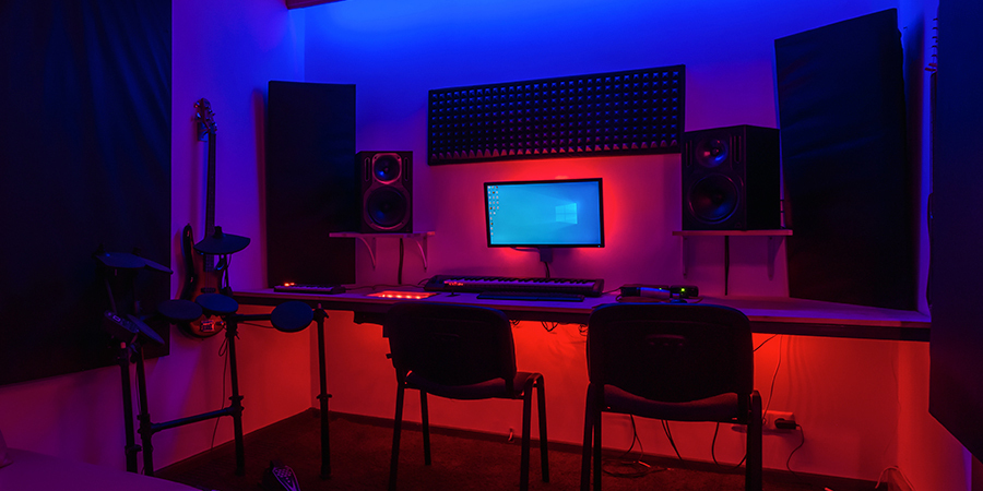 Music studio with RGB red and blue LED lighting, featuring computer, speakers, and instruments.