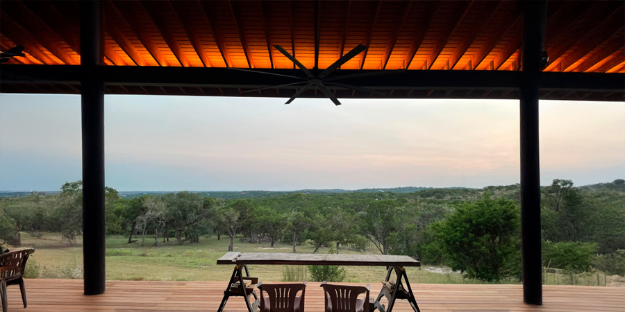  A deck with a table and chairs overlooking a beautiful landscape. The deck is illuminated with warm lighting, making it a perfect spot to relax and enjoy the view.