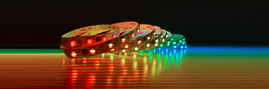 A close-up view of vibrant LED strip lights in red, green, and blue colors arranged on a table with a dark background.