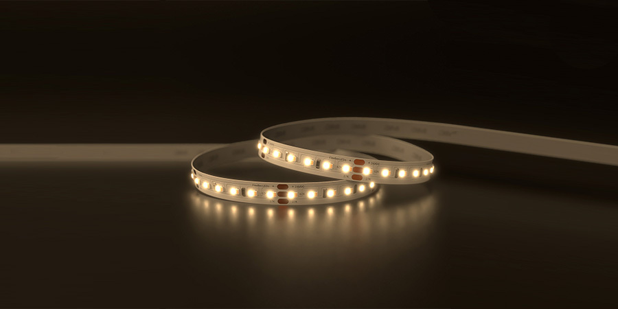 A close-up view of a warm white LED strip light with labeled color temperatures, showing its smooth glow and flexible design on a dark background.